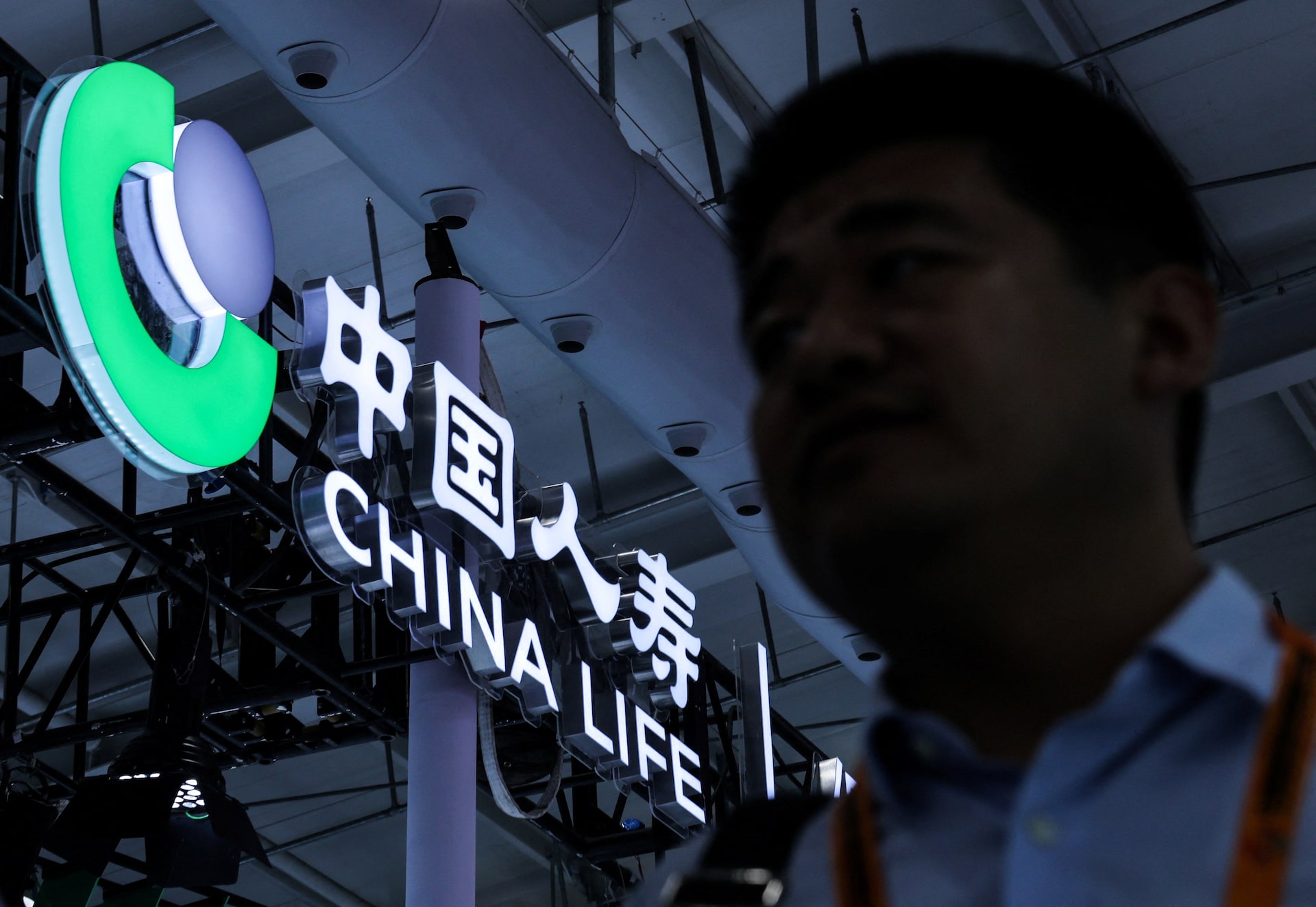 Homem passa diante do logótipo da China Life numa feira em Pequim.
