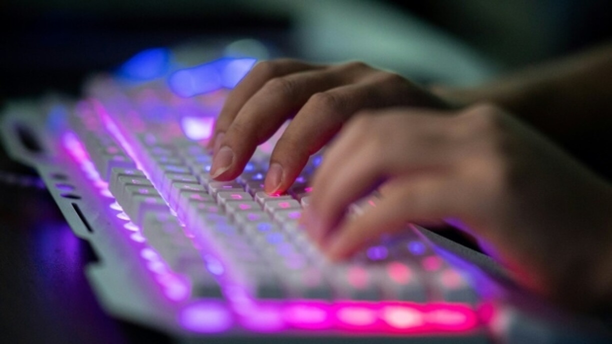 Mãos a escrever num teclado iluminado.