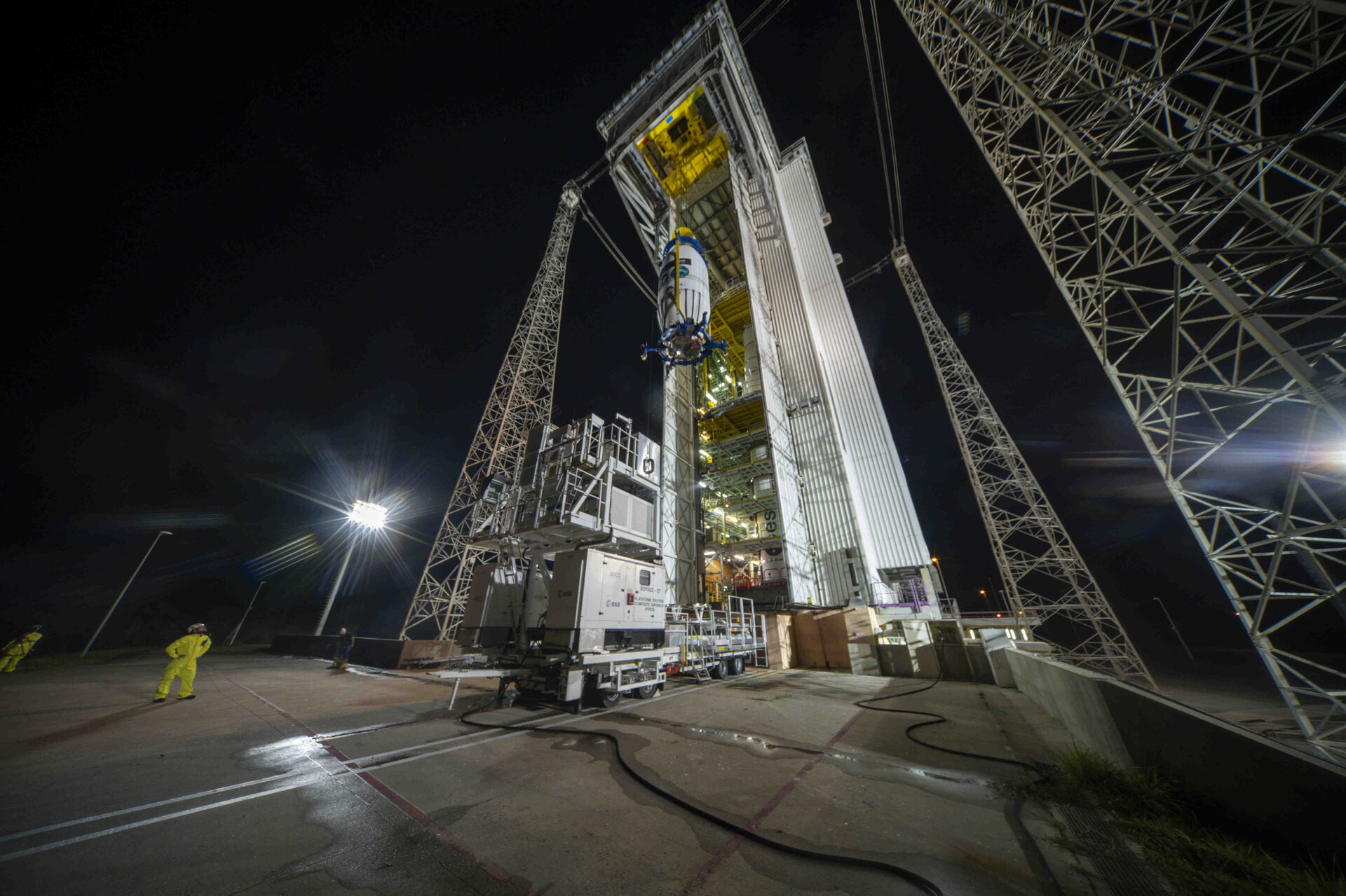 Coifa com FLEX e Sentinel-3C a ser içada junto à torre de lançamento durante a noite.