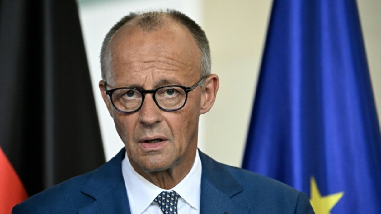 Friedrich Merz diante de bandeiras alemã e europeia.