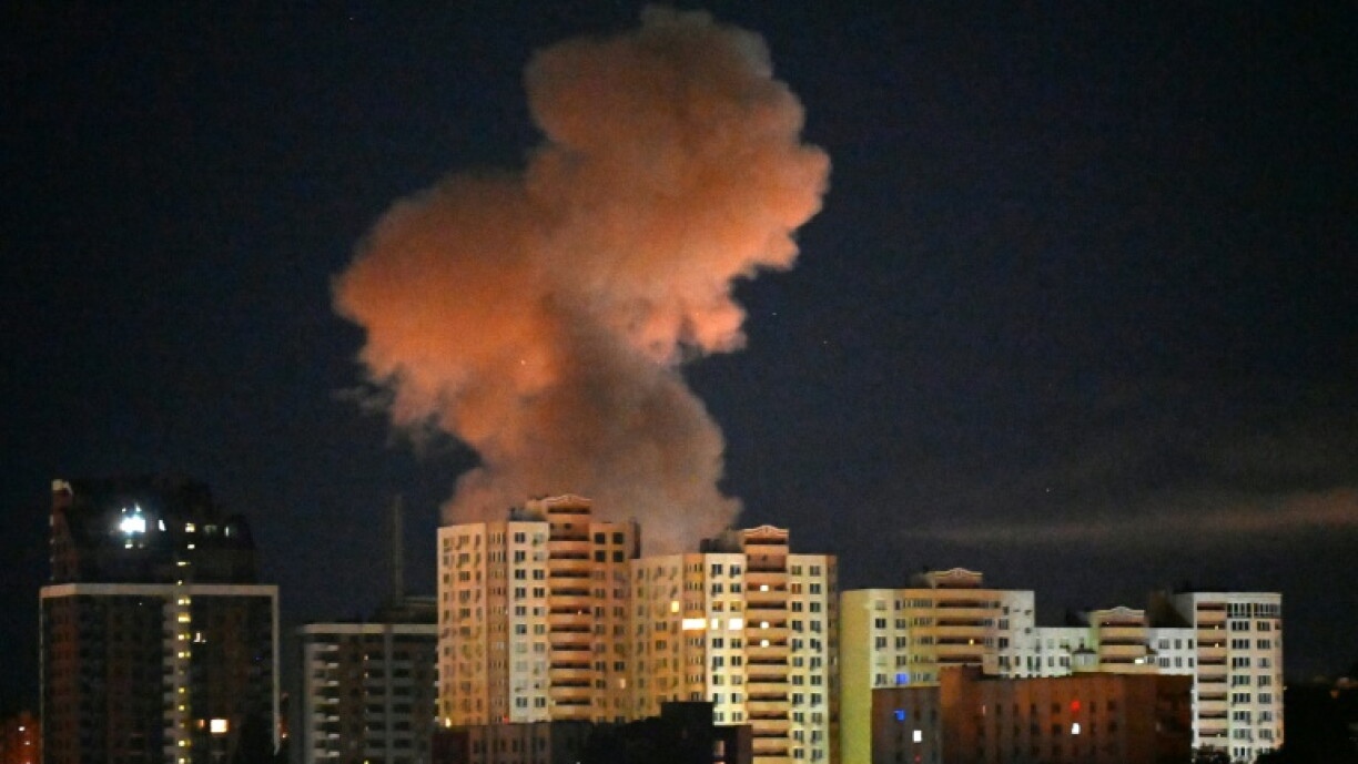 Fumo de uma explosão sobre edifícios de Kyiv durante a noite.