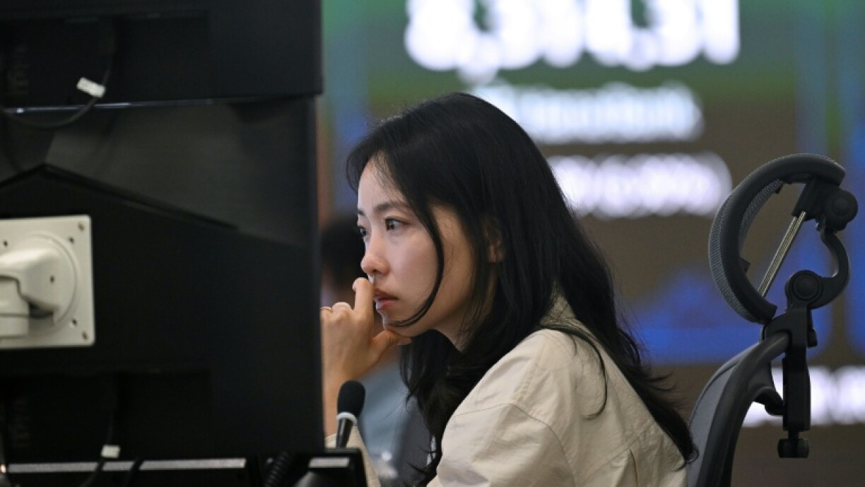 Mulher diante de um monitor num espaço de negociação financeira.