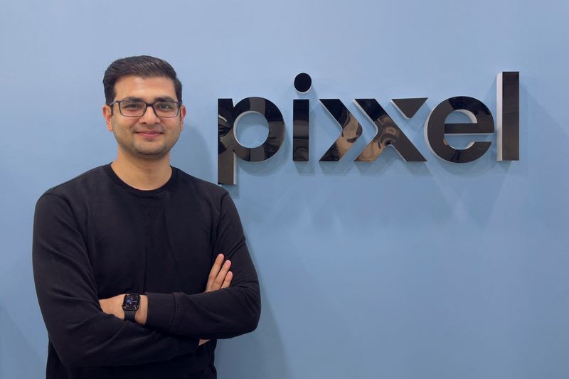 Awais Ahmed, fundador da Pixxel, diante do logótipo da empresa.